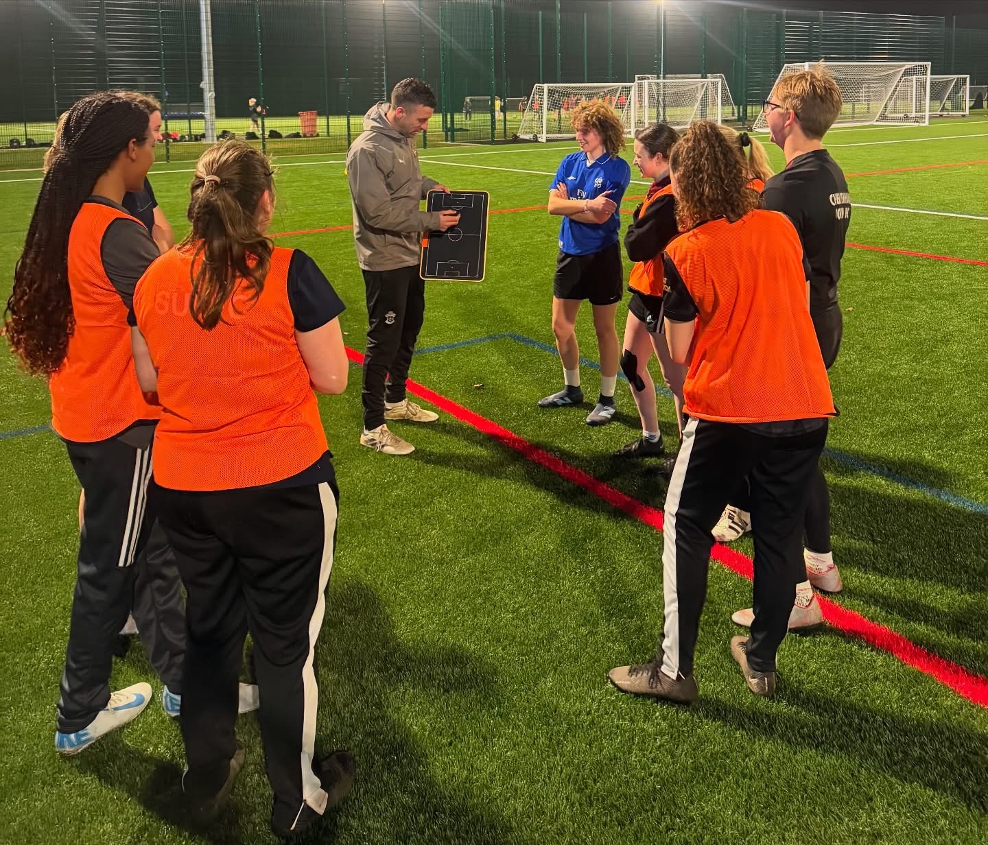 Dave holding a tactics board as players gather around on 3G at night